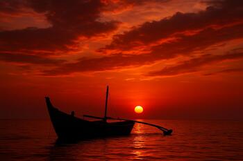 Small fishing boat against a fiery Goa sunset